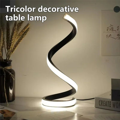 Modern Spiral LED Color Lighting Modes desk lamp glowing on a desk with warm light.
